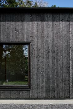 a black and white photo of a window on the side of a wooden building with trees in the background