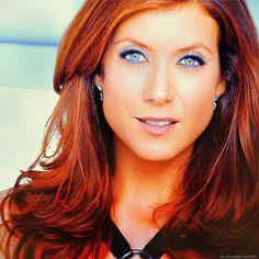 a woman with long red hair and blue eyes posing for a photo in a black halter top