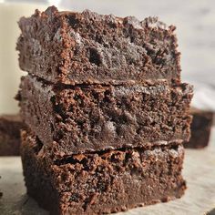 chocolate brownies stacked on top of each other with a glass of milk in the background