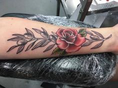 a woman's arm with a rose and leaves tattoo on the left side of her leg