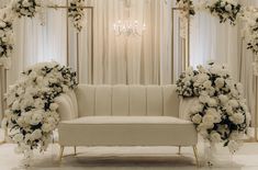 a white couch sitting under a chandelier covered in flowers