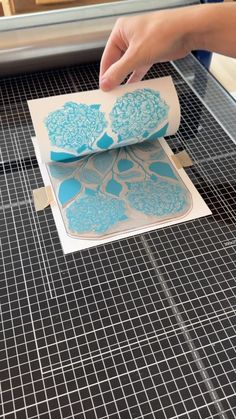 someone is making some paper with blue flowers on it