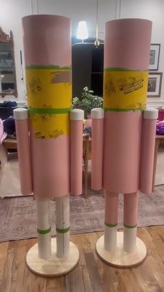 two pink vases with yellow and green tape on them sitting in front of a mirror