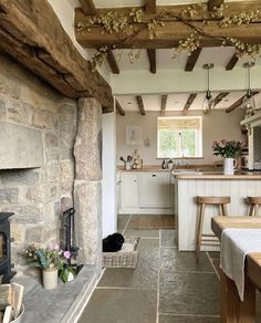 an image of a kitchen and living room in a house with stone walls, exposed beams and wood flooring