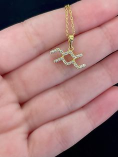 a person holding a gold necklace with the letter s on it