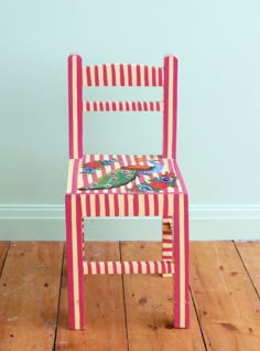 a pink and red chair sitting on top of a wooden floor next to a blue wall