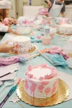 a group of people sitting around a table with cake on top of it and plates in front of them