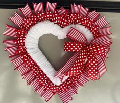 a heart shaped wreath with red and white polka dots on the front, attached to a door