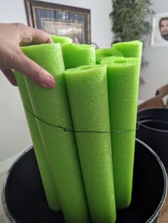 a person is holding some green sponges in a bucket