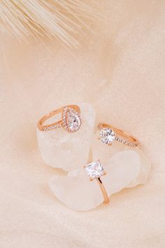 two diamond rings sitting on top of a white piece of paper next to a feather