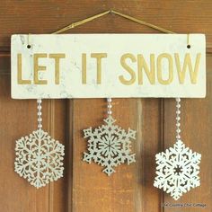 three snowflakes are hanging from a sign that says let it snow on the front door