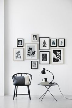 a white room with black and white pictures on the wall, a chair and table