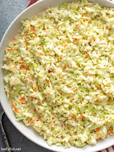 coleslaw salad in a white bowl with carrots and celery on the side