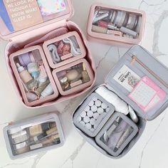 three pink travel cases filled with makeup and personal care items on a marble countertop