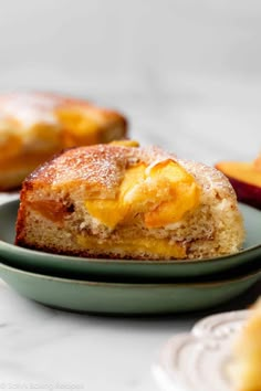 a piece of cake sitting on top of a green plate next to sliced peaches