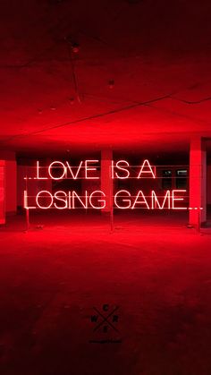 a large neon sign that says love is a losing game in the middle of an empty room