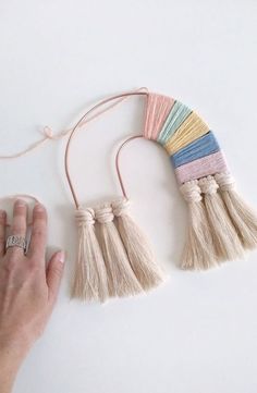 a hand holding a string with tassels attached to it on a white surface