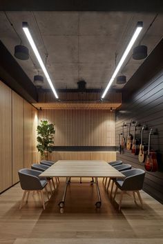 an empty conference room with guitars hanging on the wall and wooden flooring, along with two gray chairs