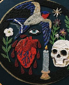 a close up of a embroidery on a piece of cloth with a heart and a candle