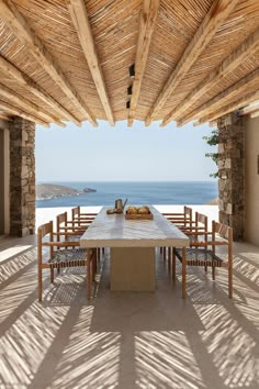 an outdoor dining area with table and chairs overlooking the ocean