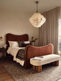 a bedroom with a large bed and a chandelier hanging over the headboard