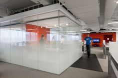 an office with glass walls and people working