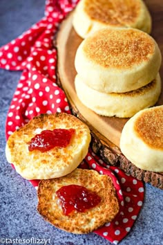 some biscuits with jam on them are sitting on a wooden board next to a red and white polka dot napkin