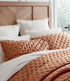 a bed with white pillows and orange comforter