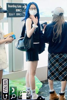 two young women standing next to each other in front of a sign that says boarding gate