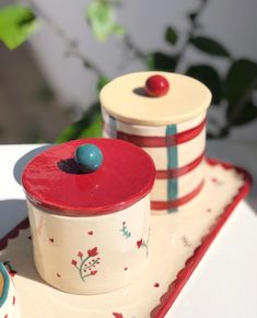 two red and white canisters sitting on top of a tray next to each other