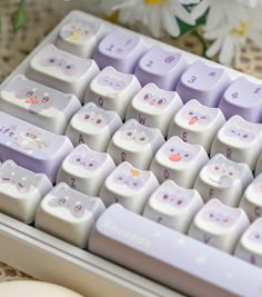 a close up of a keyboard with cats on the keys and flowers in the background