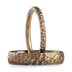 "These hand-crafted Mokume Gane bands are shown in the Twist pattern and the Oxidized Firestorm metal combination, with a low dome profile and etched and oxidized finish. Firestorm features 14k red gold, 14k yellow gold, Palladium, and sterling silver. These rings also both have a hammered finish effect for some added texture and visual interest. Mokume Gane Band - Ring 1 Pattern: Twist Palette: Firestorm Width: 2mm Size Shown: 10 Profile: Low Dome Finish: Etched & Oxidized Additional Option Heirloom Etched Bands For Gifts, Heirloom Etched Bands As Gift, Artisan Etched Jewelry For Wedding, Hand Forged Adjustable Heirloom Ring, Artisan Engraved Rings For Promise, Adjustable Hand Forged Heirloom Ring, Artisan Engraved Wedding Rings, Artisan Hand Forged Wedding Rings, Artisan Adjustable Yellow Gold Ring