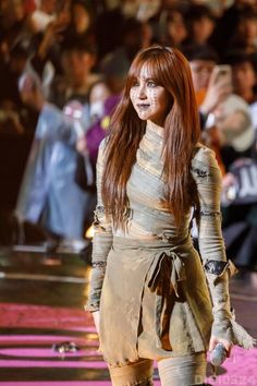 a woman with long red hair walking down a runway