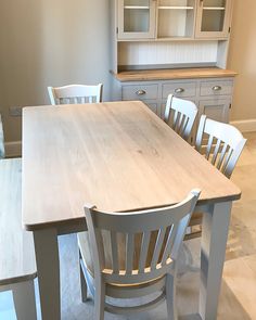 a kitchen table with chairs around it and cupboards in the backround area