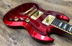 a red electric guitar sitting on top of a wooden floor