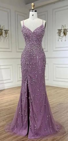 Elegance meets sophistication in our Lavender Sleeveless Pearl and Bead Embellished Front Slit Gown. This exquisite, one-of-a-kind design is perfect for making a statement at any special occasion. The delicate blend of lavender hue, intricate pearl and bead embellishments, and flowing silhouette come together to create a truly show-stopping look. Whether you're walking the red carpet or dancing the night away, our gown is sure to turn heads and make you feel like a vision of beauty. Production t Lavender Gowns Elegant Prom, Beautiful Prom Dresses Purple, Purple Prom Dress Flowy, Light Purple Prom Dress Lavender, Lilac Evening Gown, Purple Grad Dresses, Pearl Prom Dress, Sparkly Purple Dress, Lavendar Dress