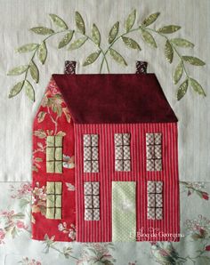 a red house with green leaves on the top and bottom is made out of fabric