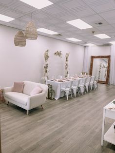 a room filled with tables and chairs next to a white table cloth covered couch in front of a mirror