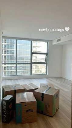 boxes are stacked on the floor in an empty room with large windows and wooden floors