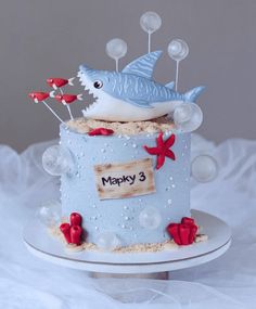 a blue birthday cake with a shark on it's top and bubbles in the air