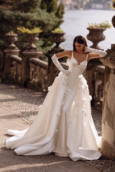 a woman in a wedding dress leaning against a stone wall