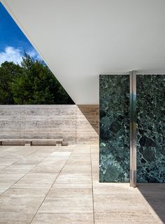 an empty room with marble walls and wooden benches on the outside, looking out into the outdoors