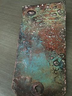 a piece of metal that is on top of a table and has some paint splattered on it