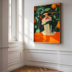 an orange painting hangs in the corner of a room with white walls and wood flooring