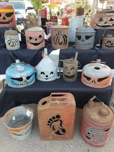 several jugs with faces painted on them sitting on a table in front of other items