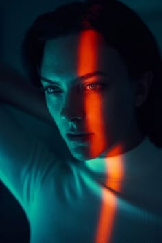 a woman in white shirt with red and green light shining on her face from behind