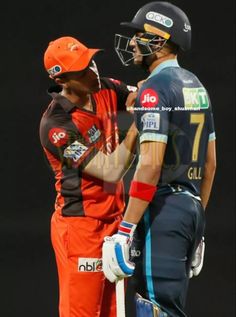 two men standing next to each other wearing helmets and holding cricket bats in their hands