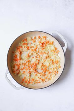 carrots and onions cooking in a pot on a white table top with a spoon