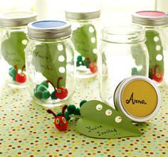 some glass jars filled with green plants and red berries on top of a polka dot table cloth