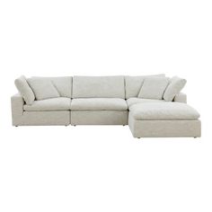 a white sectional couch with pillows on the back and foot rest in front of it